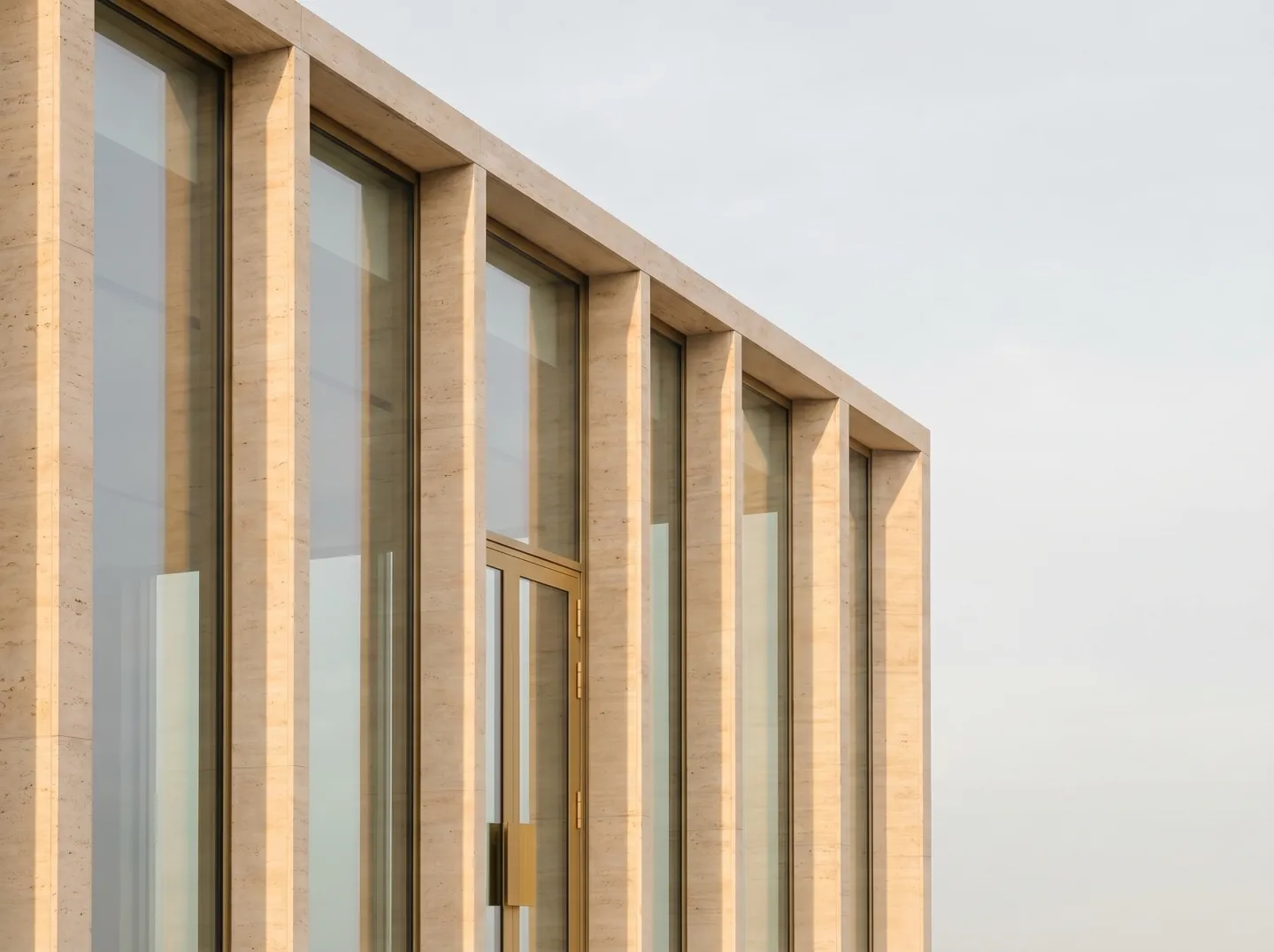 Fachada moderna de piedra con un ritmo de columnas y cristal